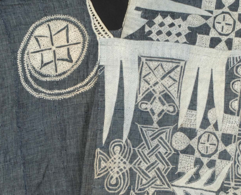 Blauwe katoenen boubou uit het begin van de 20e eeuw, Nigeria. De halslijn en de voorzak zijn versierd met een gedetailleerd wit borduursel met abstracte motieven. (TM-2770-1)