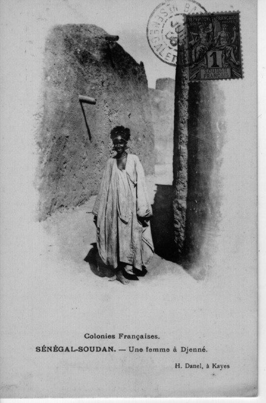 Zwart-witfoto van een vrouw die een boubou draagt in Djenné, Mali, in het begin van de 20e eeuw. Hoewel boubous meestal herenkleding zijn, dragen vrouwen ze soms ook. 9 RV-5898-37)
