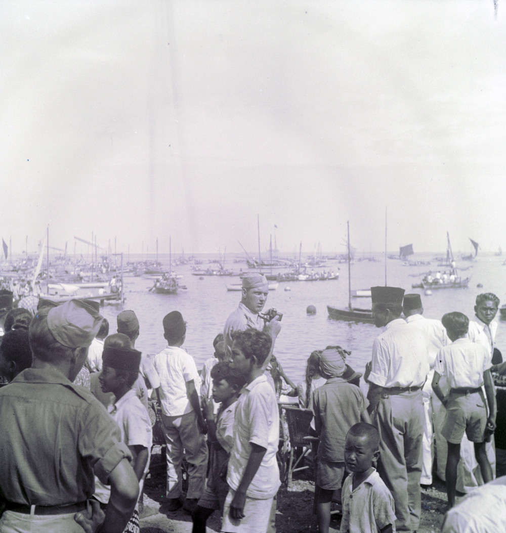 Nederlandse militair met camera tijdens de roeiwedstrijden met prauwen ter gelegenheid van Koninginnedag, Makassar op Sulawesi, 1948-1949. (TM-10028558) © Erven C.J. Taillie