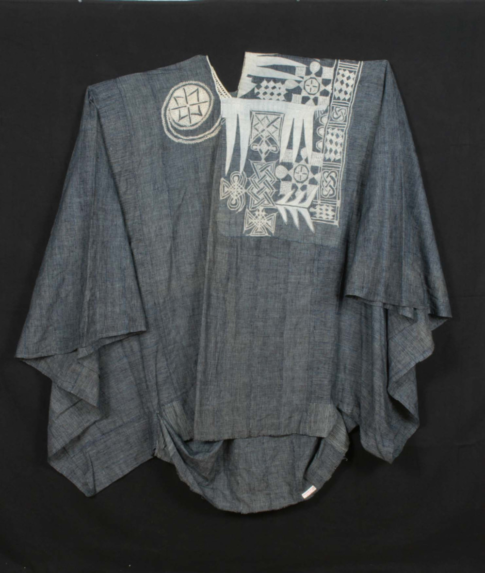 Blauwe katoenen boubou uit het begin van de 20e eeuw, Nigeria. De halslijn en de voorzak zijn versierd met een gedetailleerd wit borduursel met abstracte motieven. (TM-2770-1)