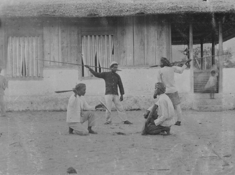 2. Demonstratie van speerwerpen en vechten met zwaard en schild door mannen in een dorp op het eiland Buru, 1905-1920. Fotograaf onbekend. (TM-60045885)