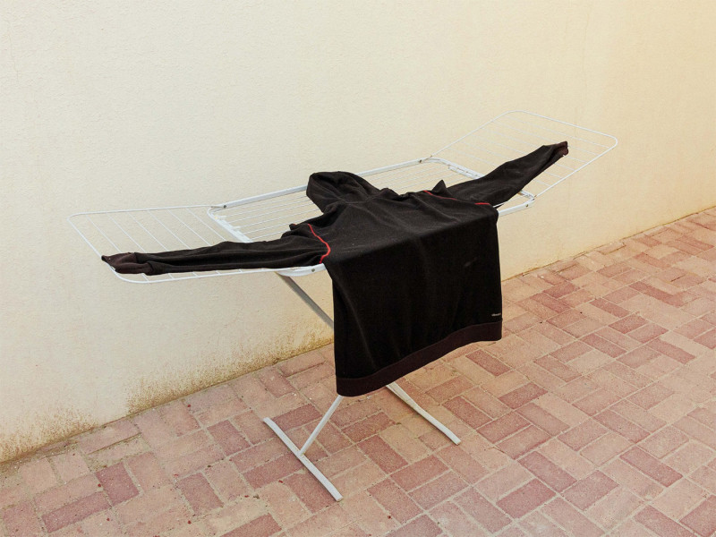 Tired:  A dark hoodie hangs outstretched on a metal clothes drying rack in an outdoor alley in Doha, Qatar, March 11, 2026.