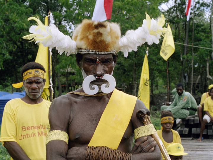 Portret van een Asmat Papua man tijdens een verkiezingsbijeenkomst van de Golkar-partij in Agats, 30-03-2004. Fotograaf: Wim van Oijen. © Tropenmuseum/Nationaal Museum van Wereldculturen (TM-20041260)